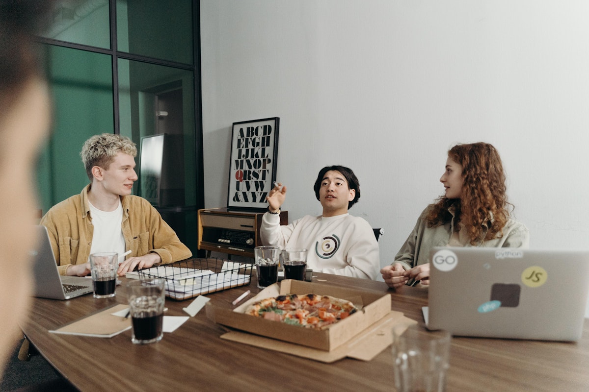 pause déjeuner autour d'une table avec une pizza dans une startup