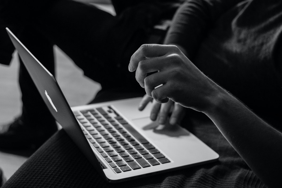 Mains qui travaillent sur un Mac. Photo en noir et blanc.