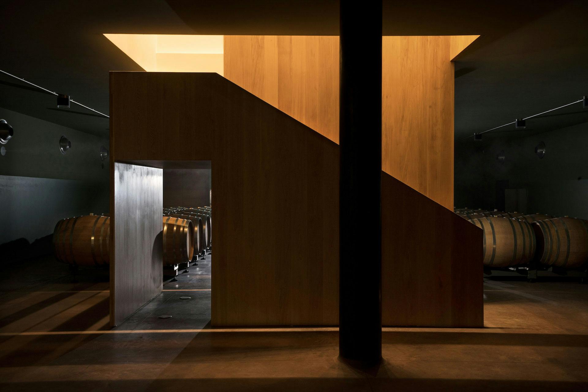 Architectural wooden staircase in the barrel room of the winery with some barrels in the background