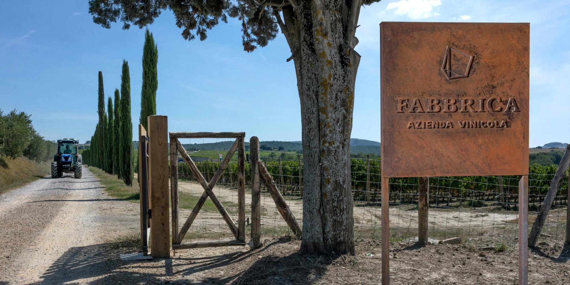 Tours-HERO- Fabbrica con trattore Entrata di Fabbrica con un trattore sulla strada bianca, i cipressi e il cartello