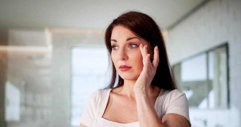 woman lightly touching the skin next to her eye