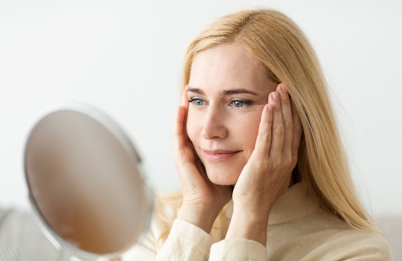 woman with blonde hair observing her appearance