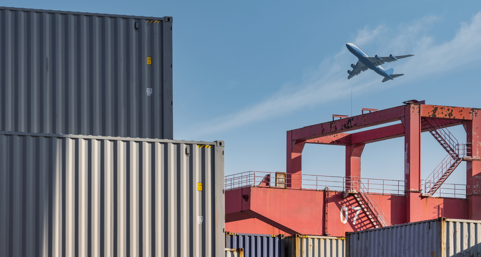 Plane flying over shipping containers