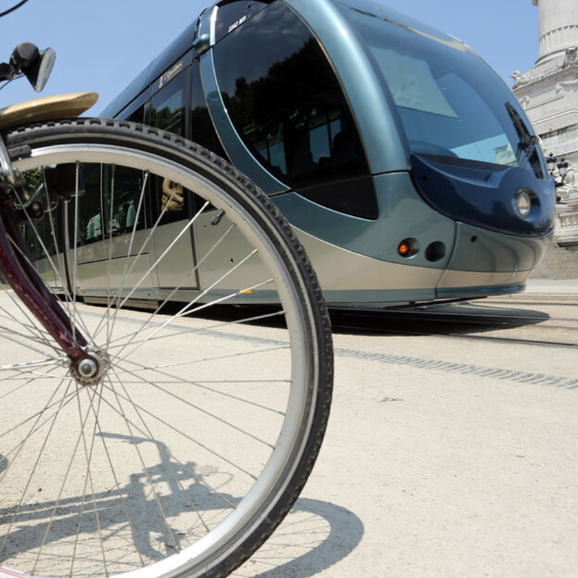 Zoom sur une roue de vélo avec un tramway en arrière-plan.