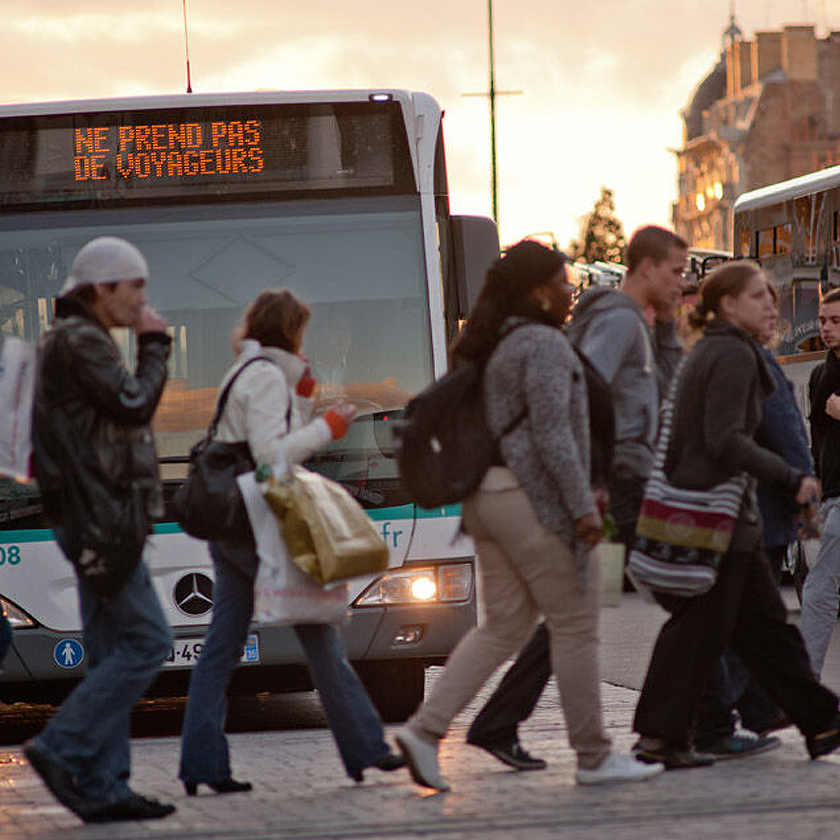 Passagers traversant au passage clouté devant un bus