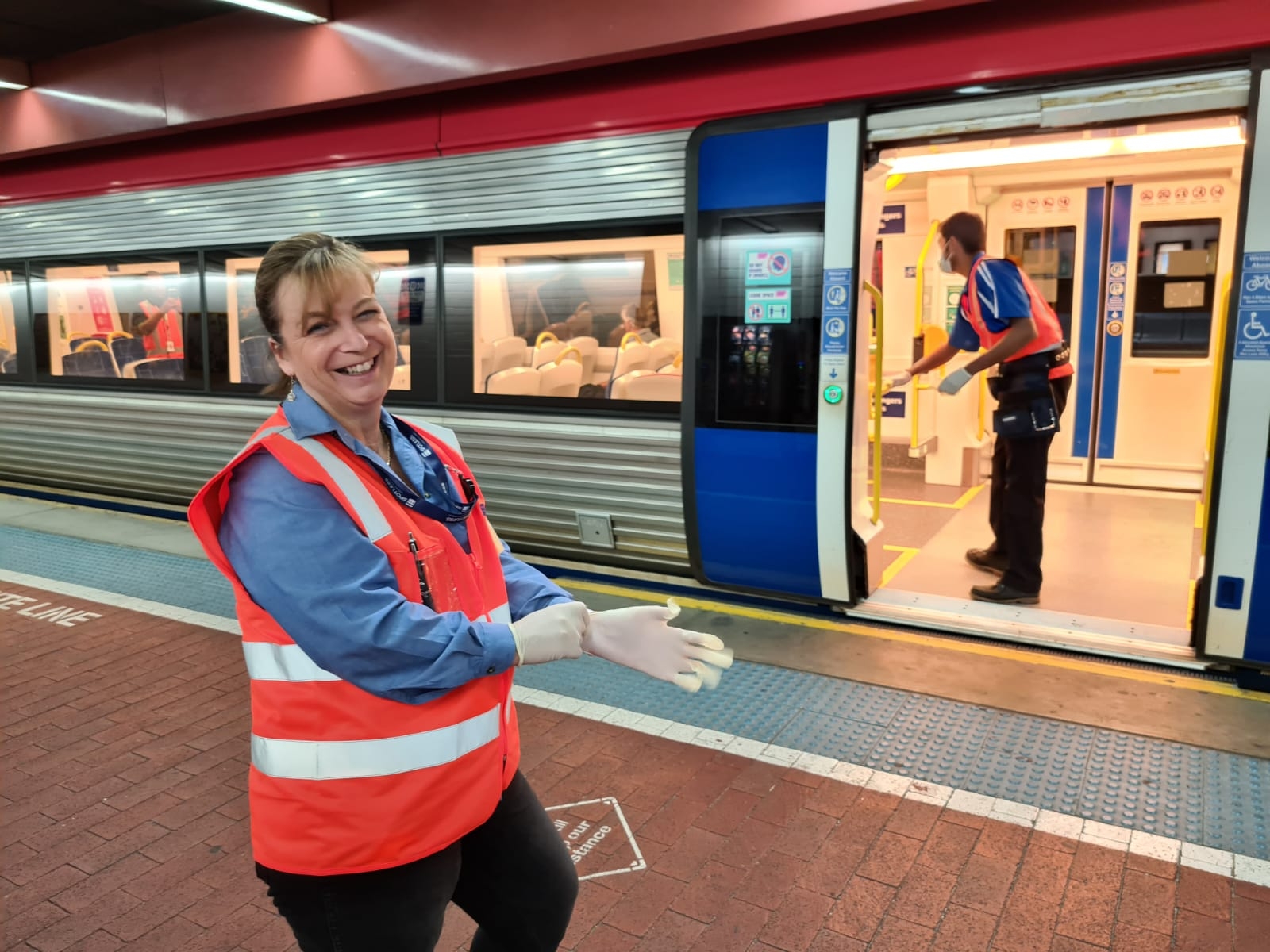 Collaboratrice souriante de Keolis Downer devant un des trains d'Adélaïde