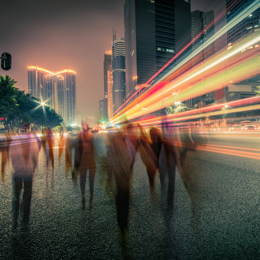 image of long exposure showing pedestrians and vehicules in a city at night 