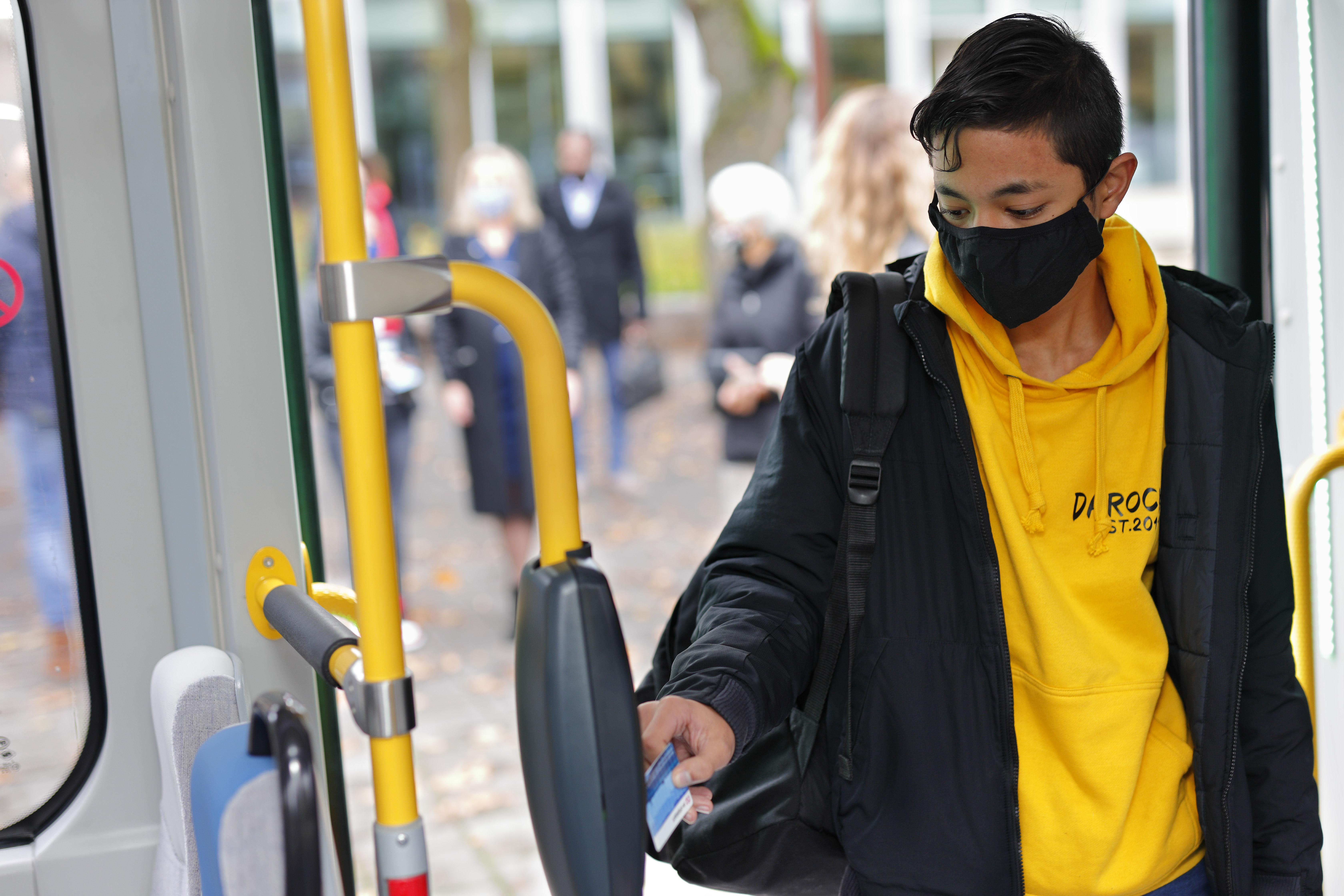 Jeune étudiant badgeant son titre de transport à l'entrée d'un autobus