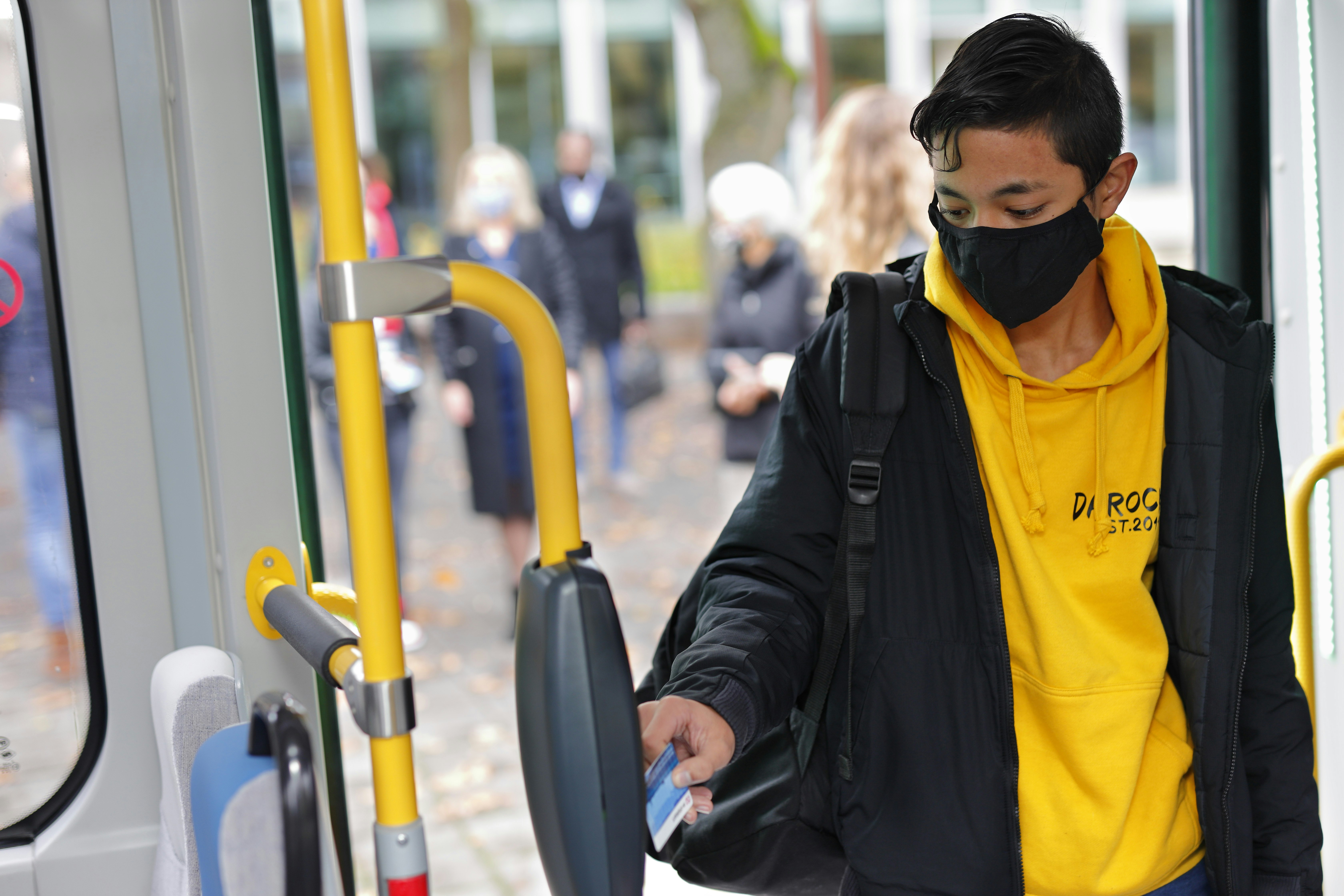 Young man tagging his ticket at the entrance of a bus