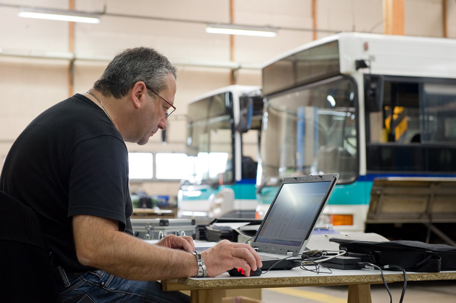 A man working on a computer at a bus depot