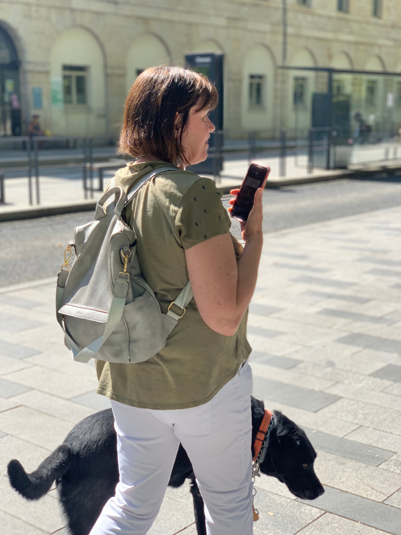 Personne malvoyante avec un chien guide se déplaçant avec l'application Ezymob