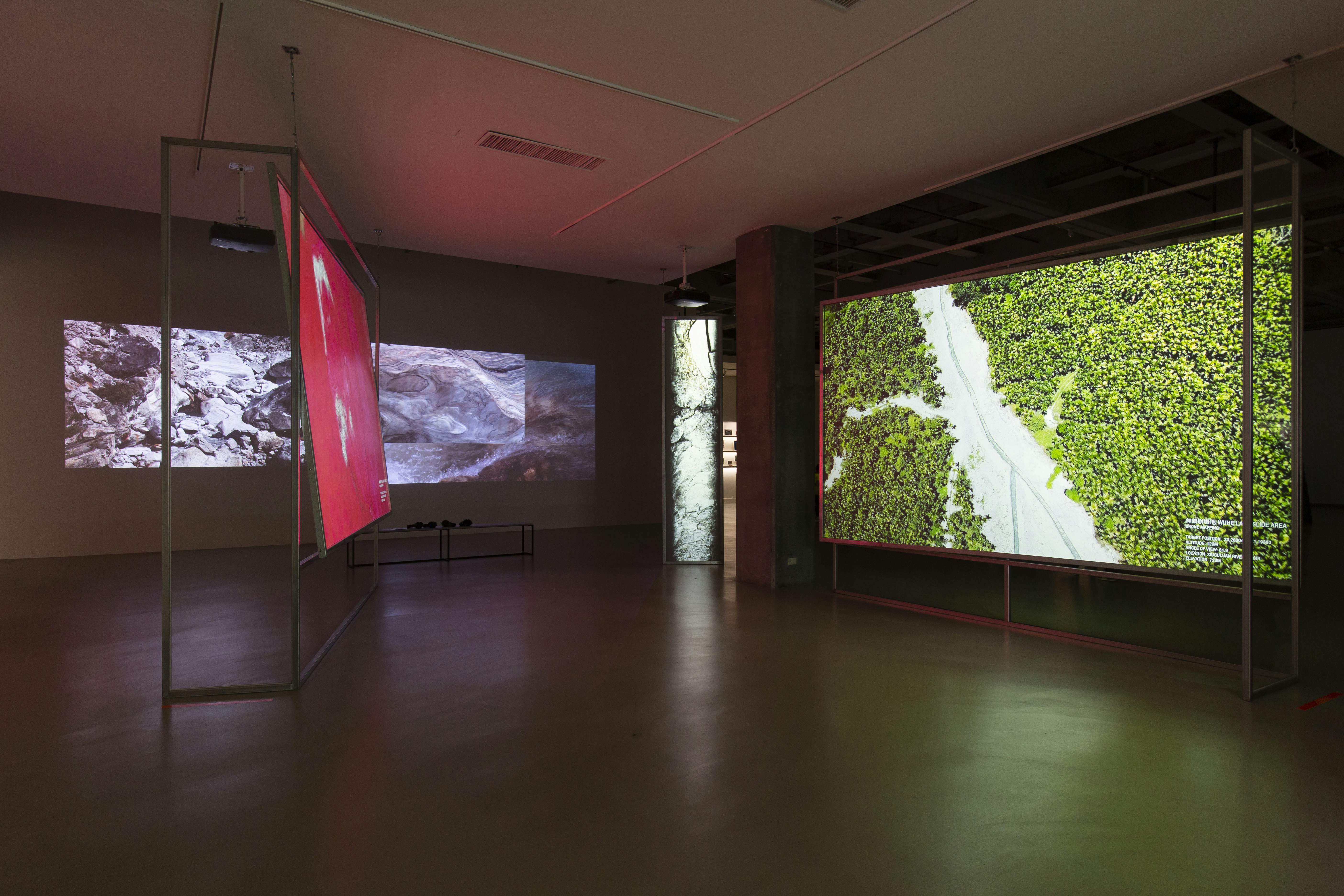 Multi-screened video installation showing rock formations and greenery.