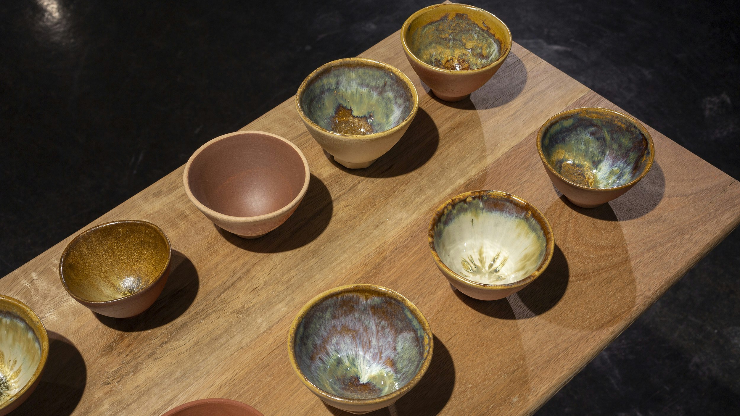 Image: Ray Chan See Kwong, NEW RE NEW (detail), 2018, 49 teacups: various local Chuen Lung clays, glazed and fired; produced as part of the 2018 public art and community project Hi! Hill!, by the Hong Kong Leisure and Cultural Services Department, Organised by the Art Promotion Office with Curatorial Partner (art in-situ): Make A Difference Institute, Hong Kong; courtesy the artist; Mounted on River bench, recycled spotted gum bench and assorted hardwood legs, wax, by Bryden Williams of Mount Framing, commissioned by 4A Centre for Contemporary Asian Art, 2021; photo: Christian Capurro for Drawn by stones, presented by 4A Centre for Contemporary Asian Art at Counihan Gallery, Brunswick, 2021