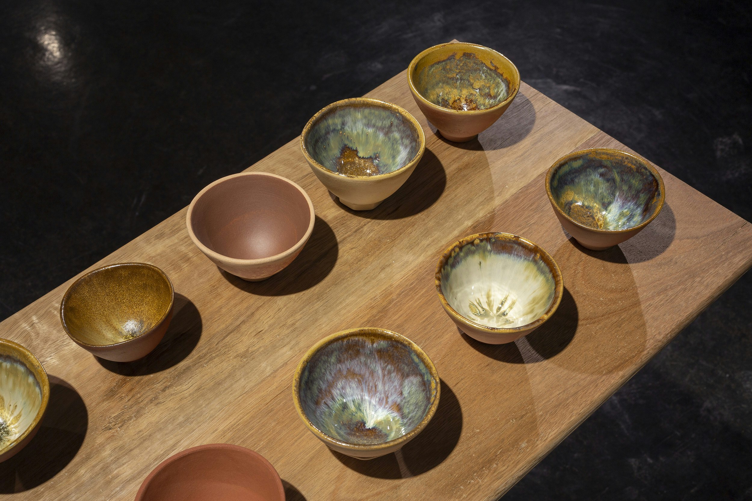 Image: Ray Chan See Kwong, NEW RE NEW (detail), 2018, 49 teacups: various local Chuen Lung clays, glazed and fired; produced as part of the 2018 public art and community project Hi! Hill!, by the Hong Kong Leisure and Cultural Services Department, Organised by the Art Promotion Office with Curatorial Partner (art in-situ): Make A Difference Institute, Hong Kong; courtesy the artist; Mounted on River bench, recycled spotted gum bench and assorted hardwood legs, wax, by Bryden Williams of Mount Framing, commissioned by 4A Centre for Contemporary Asian Art, 2021; photo: Christian Capurro for Drawn by stones, presented by 4A Centre for Contemporary Asian Art at Counihan Gallery, Brunswick, 2021