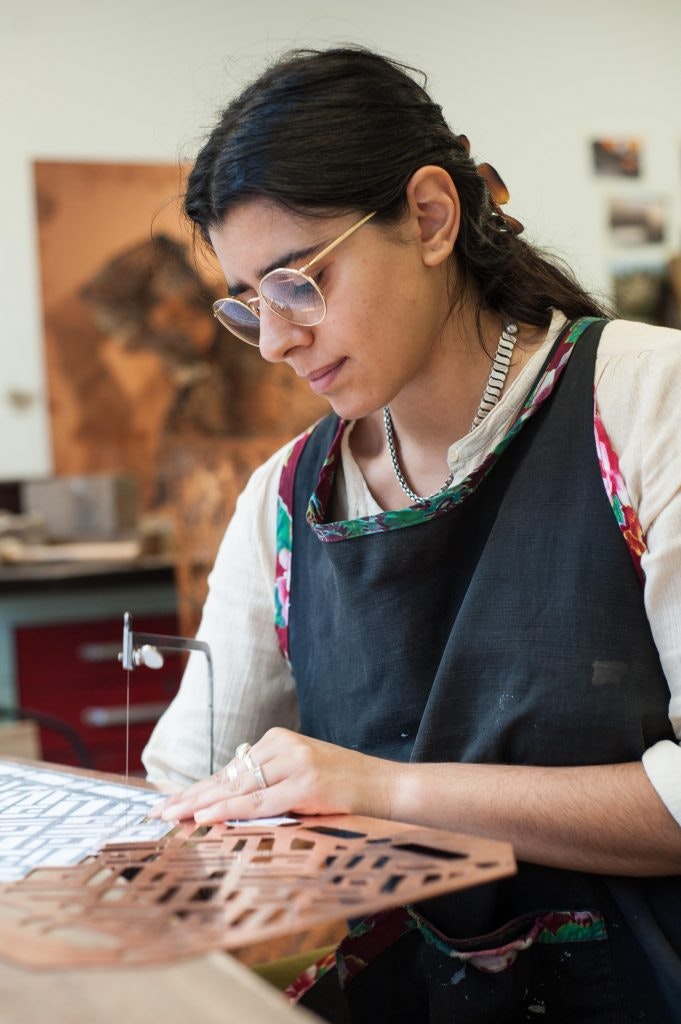 A profile photo of artist Shireen Taweel at work in her studio