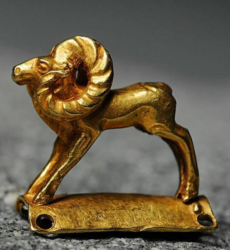 A yellow metal scuplure resembling a ram.