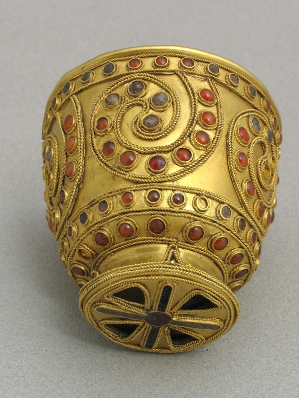 A gold goblet with blue and red detailing.