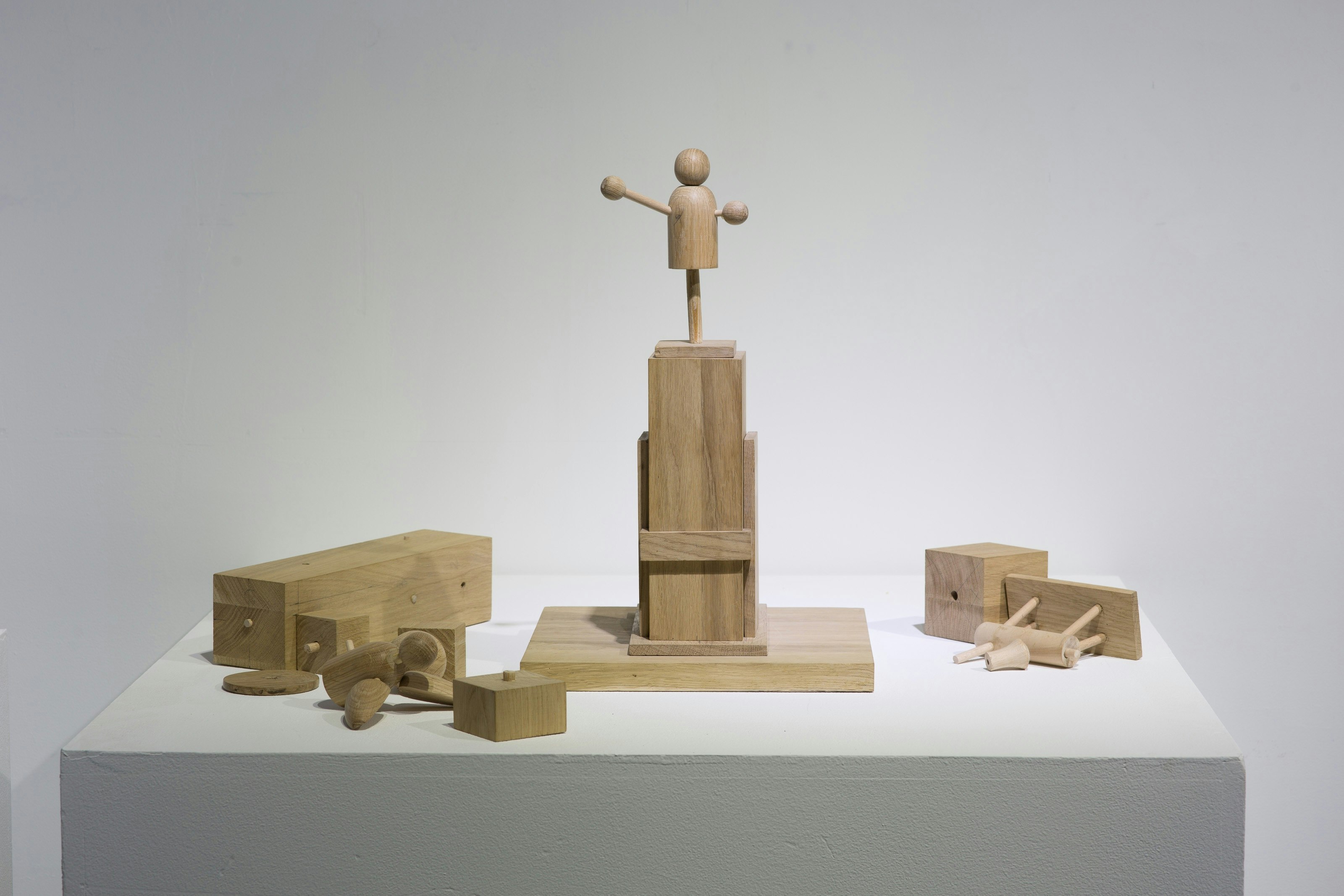 A wooden scuplture on a plinth.