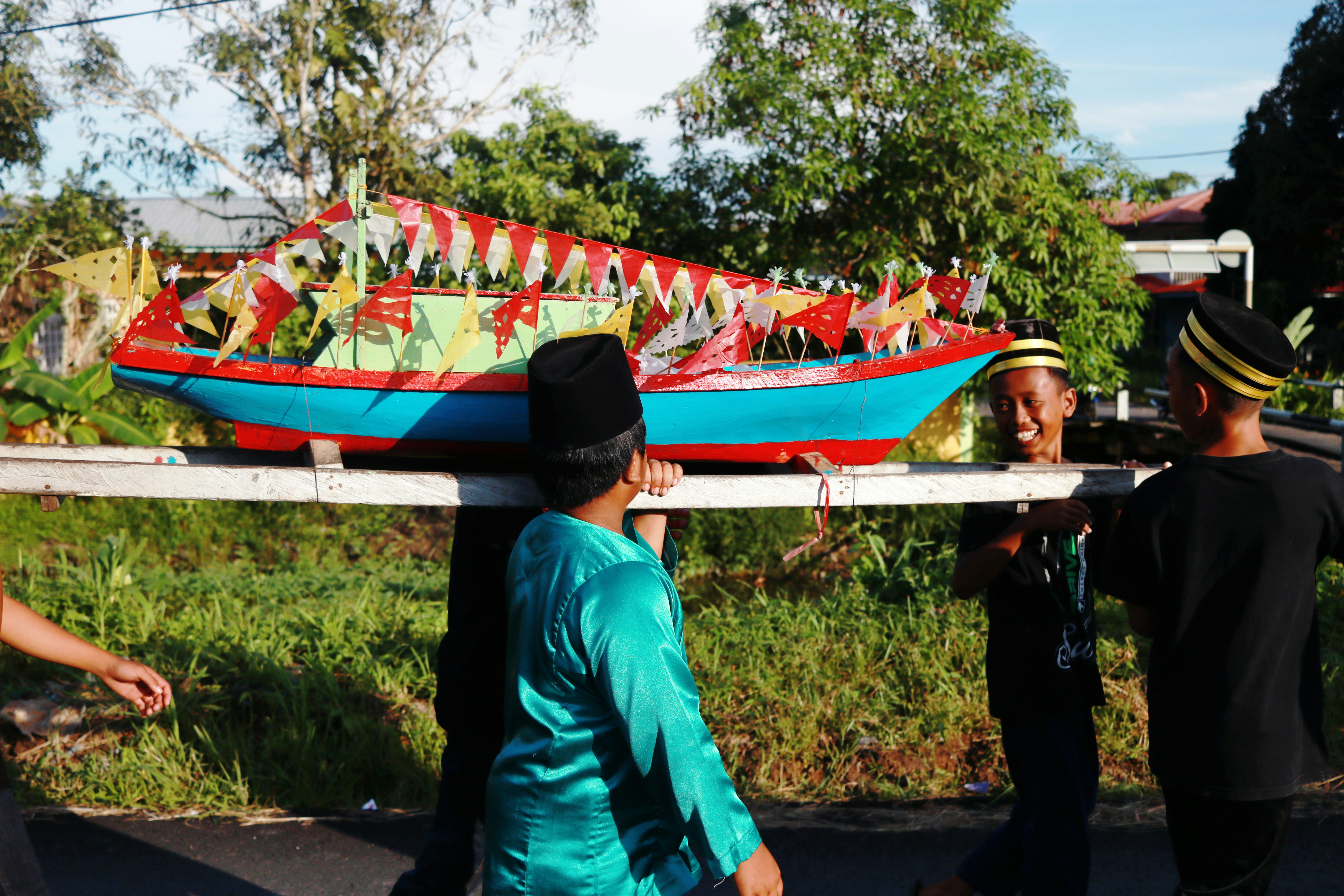 A group of people carry a small blue, red, green and gold replica of an unsungan.