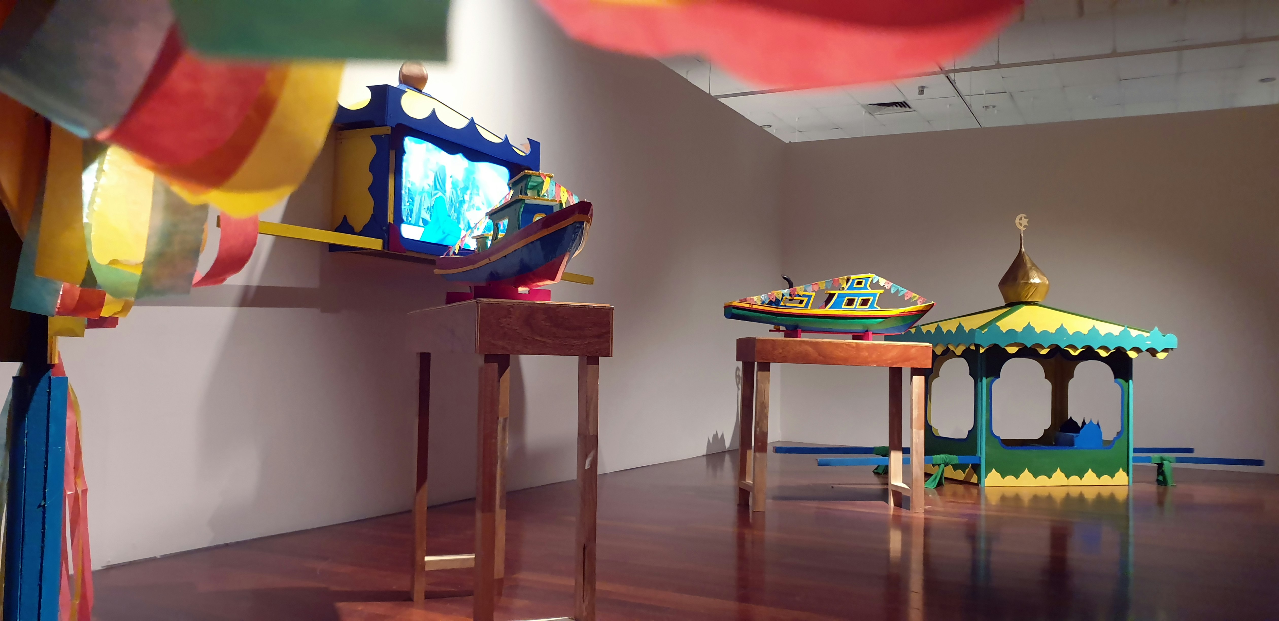 Colourful and wooden structures placed in a gallery. 