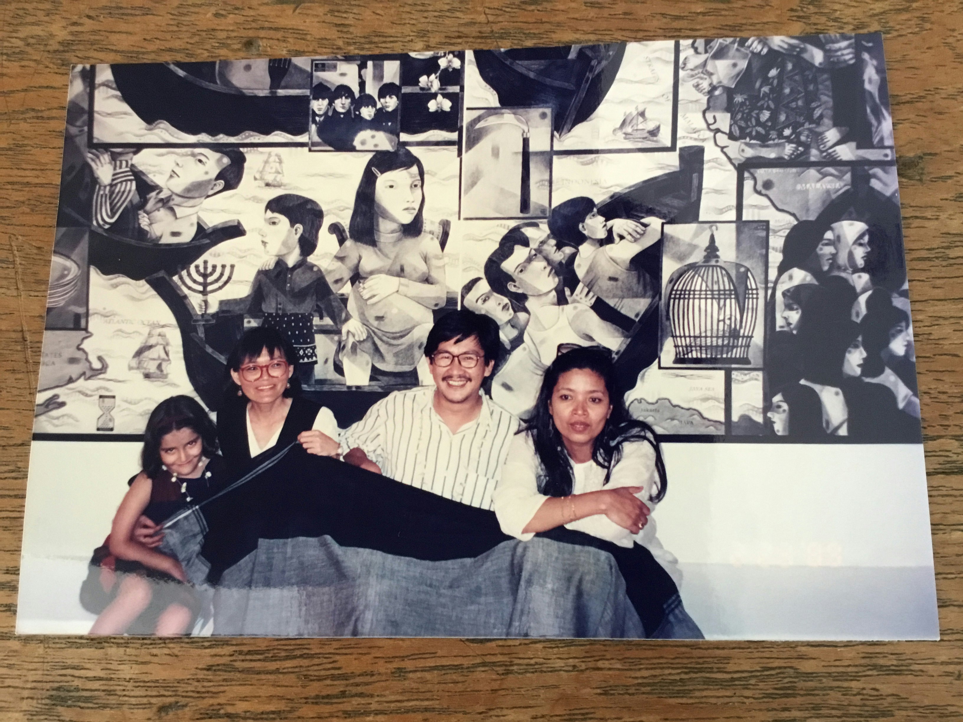 Print photo of a child, two women and a man in front of a black-and-white artwork
