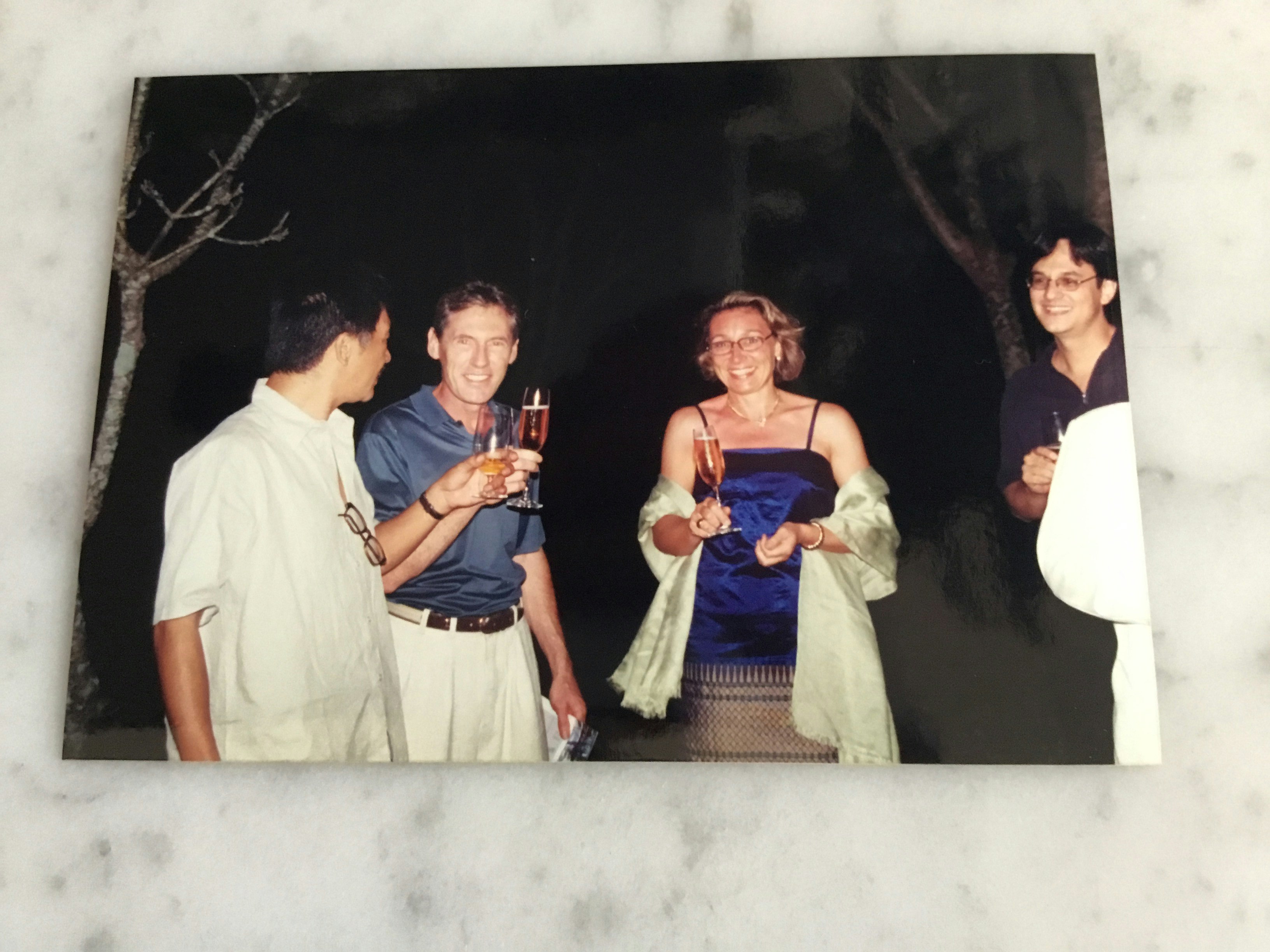 Print photo of four people holding champagne glasses outside at night