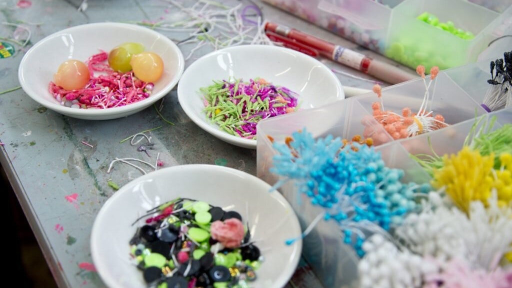 A table with bowls and containers full of decorations from which to make zodiac flower charms.