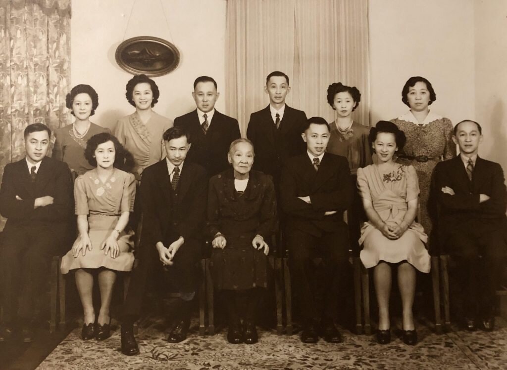 A photograph of the Dion family showing 12 family members seated in two rows, dressed in formal clothing.