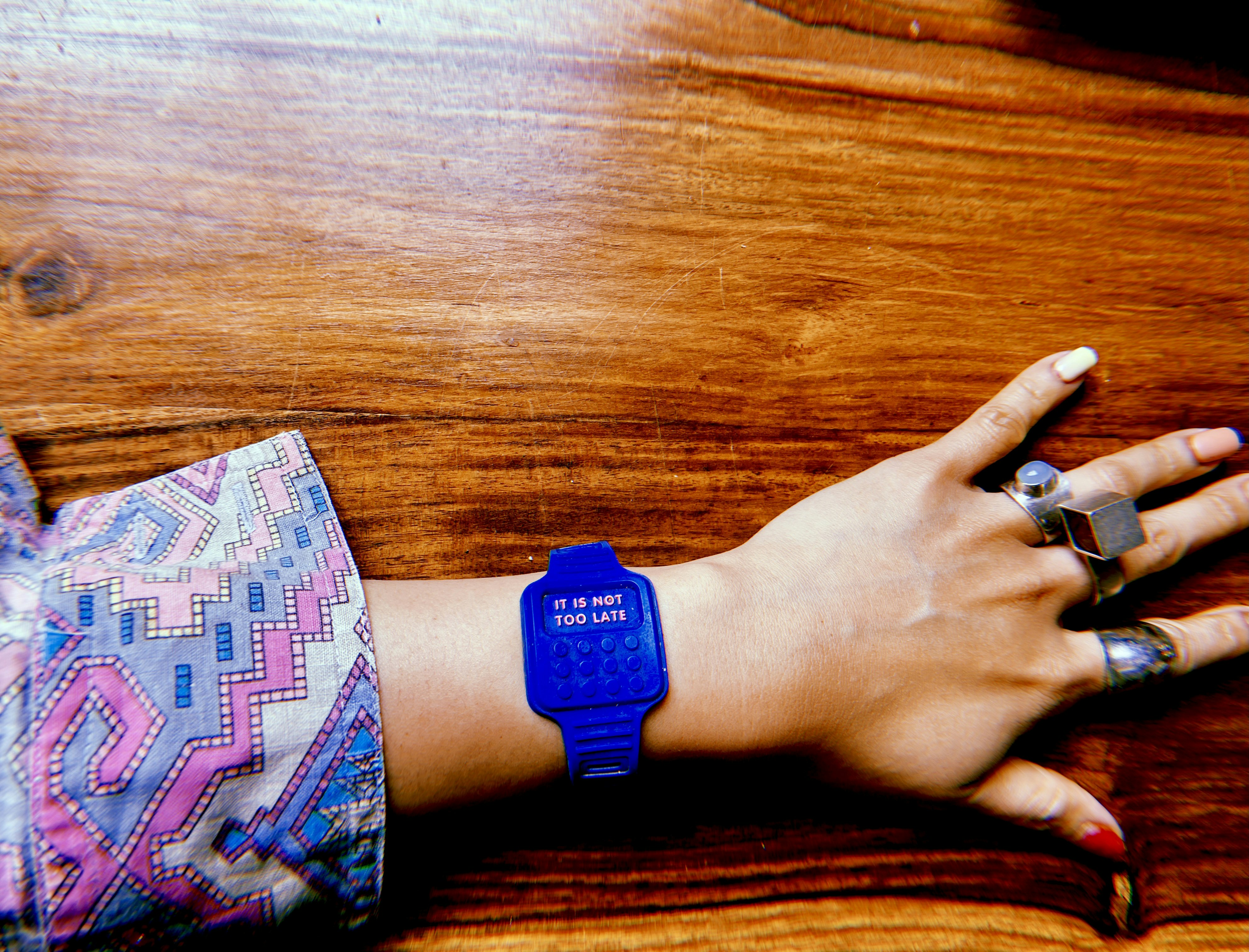 Fake, blue plastic digital watch resting on the author's arm, with the line 'It is not too late' beaming on the screen instead of hours and minutes. Photo: Mariam Arcilla