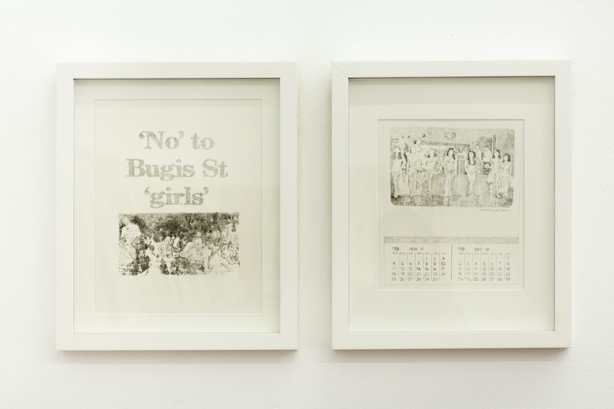 Two graphite prints in white frames on a gallery wall: writing on the left says, 'No' to Bugis St 'girls', while the right has an image of a group of girls with two calendar months printed underneath.