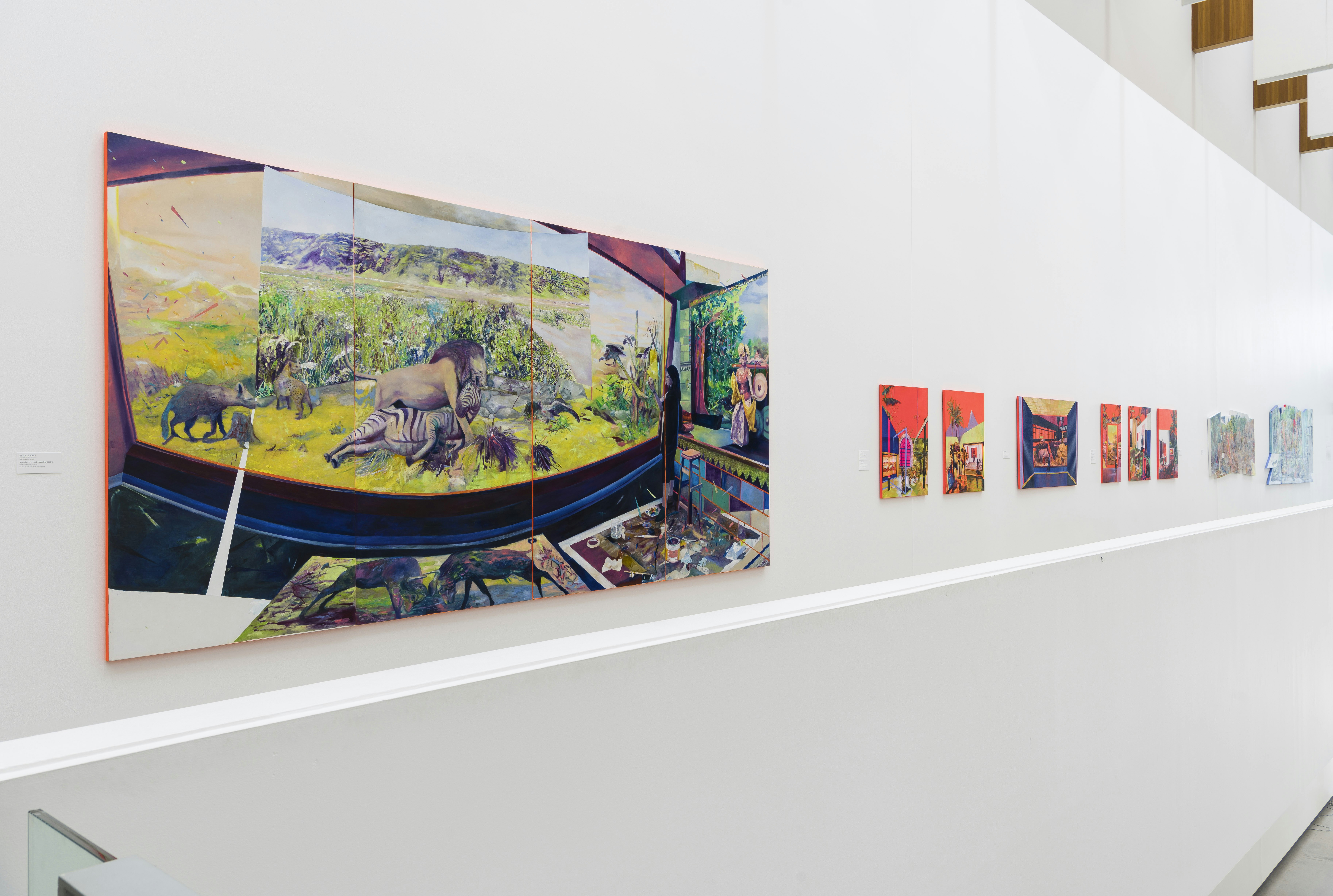 Installation view of a series of paintings, the most visible one being a panel of animals in confrontation on an open plain.