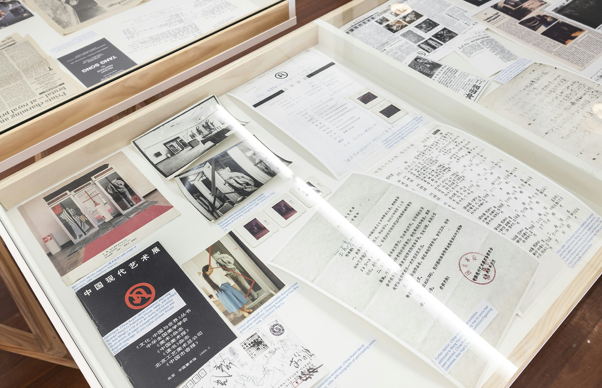 Chinese language pamphlets, newspaper clippings and photo prints in a glass display cabinet