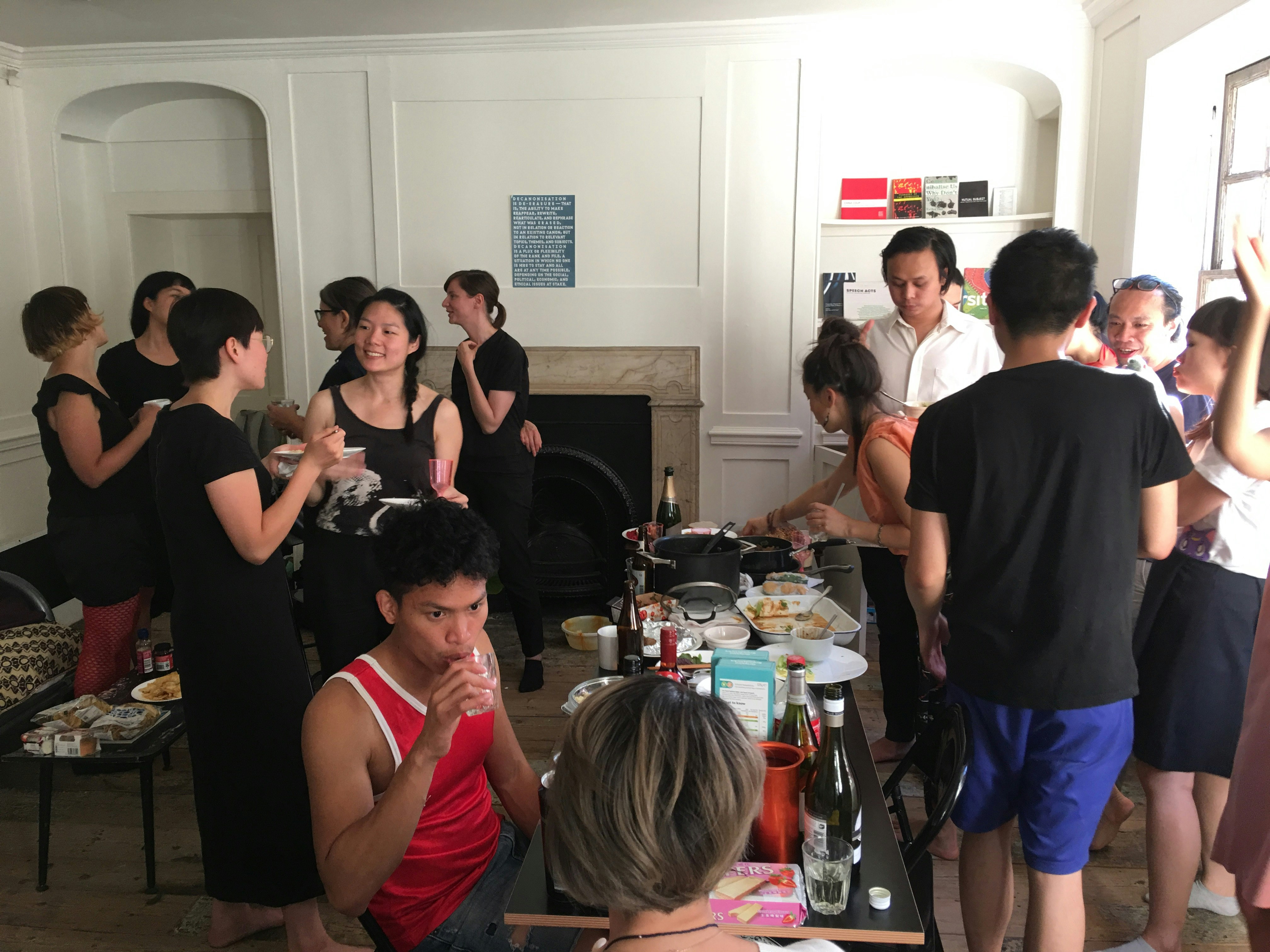 A group of artists of Asian descent talking to each other at a pot luck gathering.