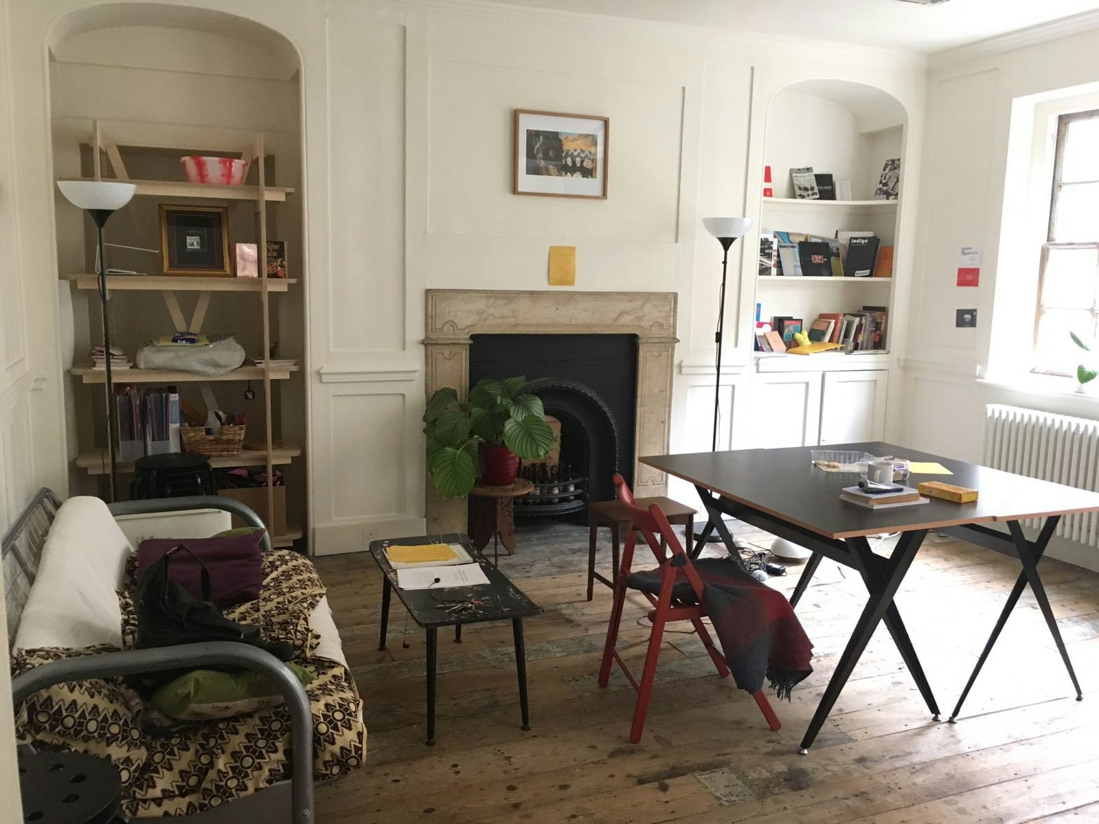 An 18th-century style salon with a fireplace, sofa and drafting table, used as an artist studio. 