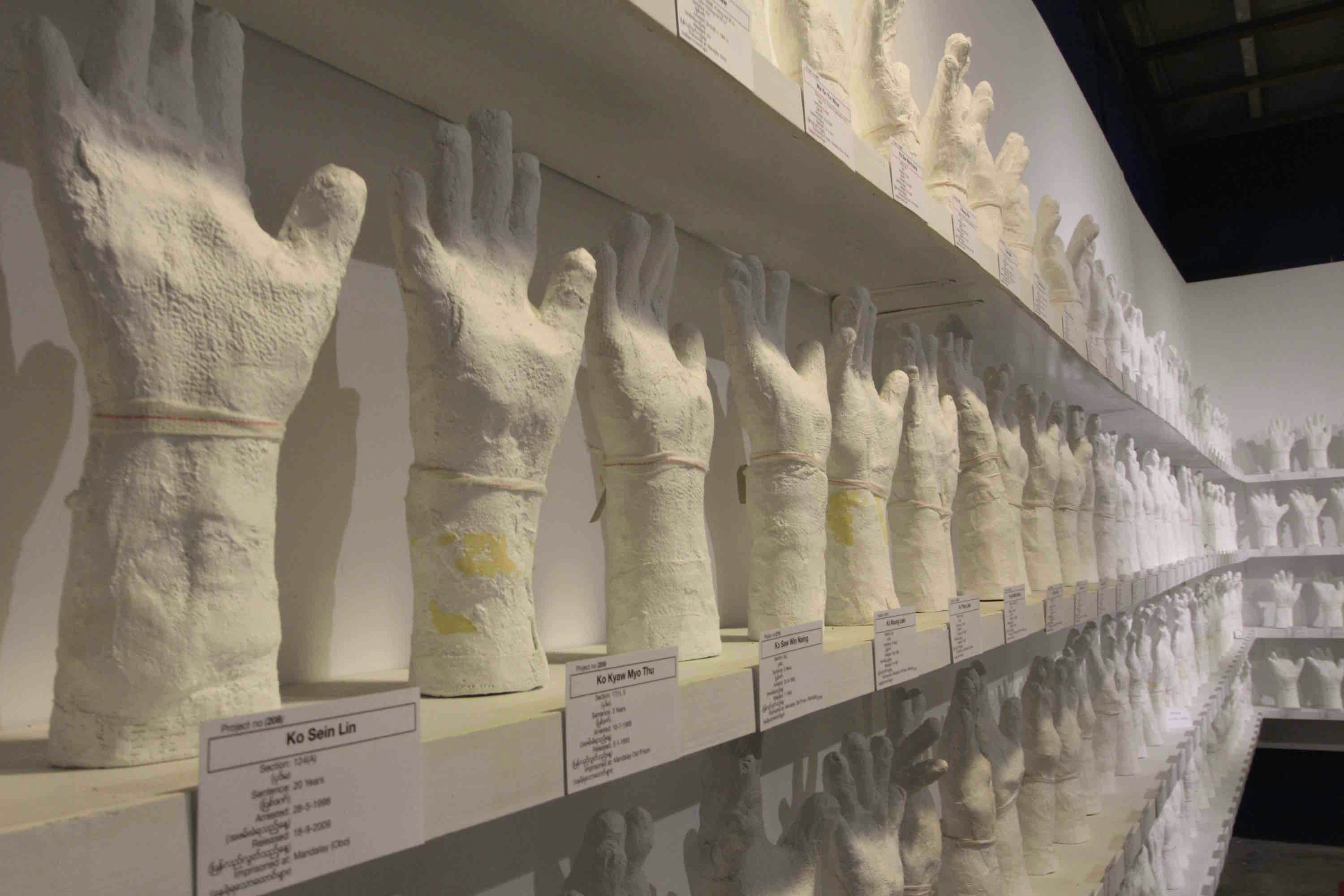 Shelves of plaster-casted hands, all raising fingertips to the sky.