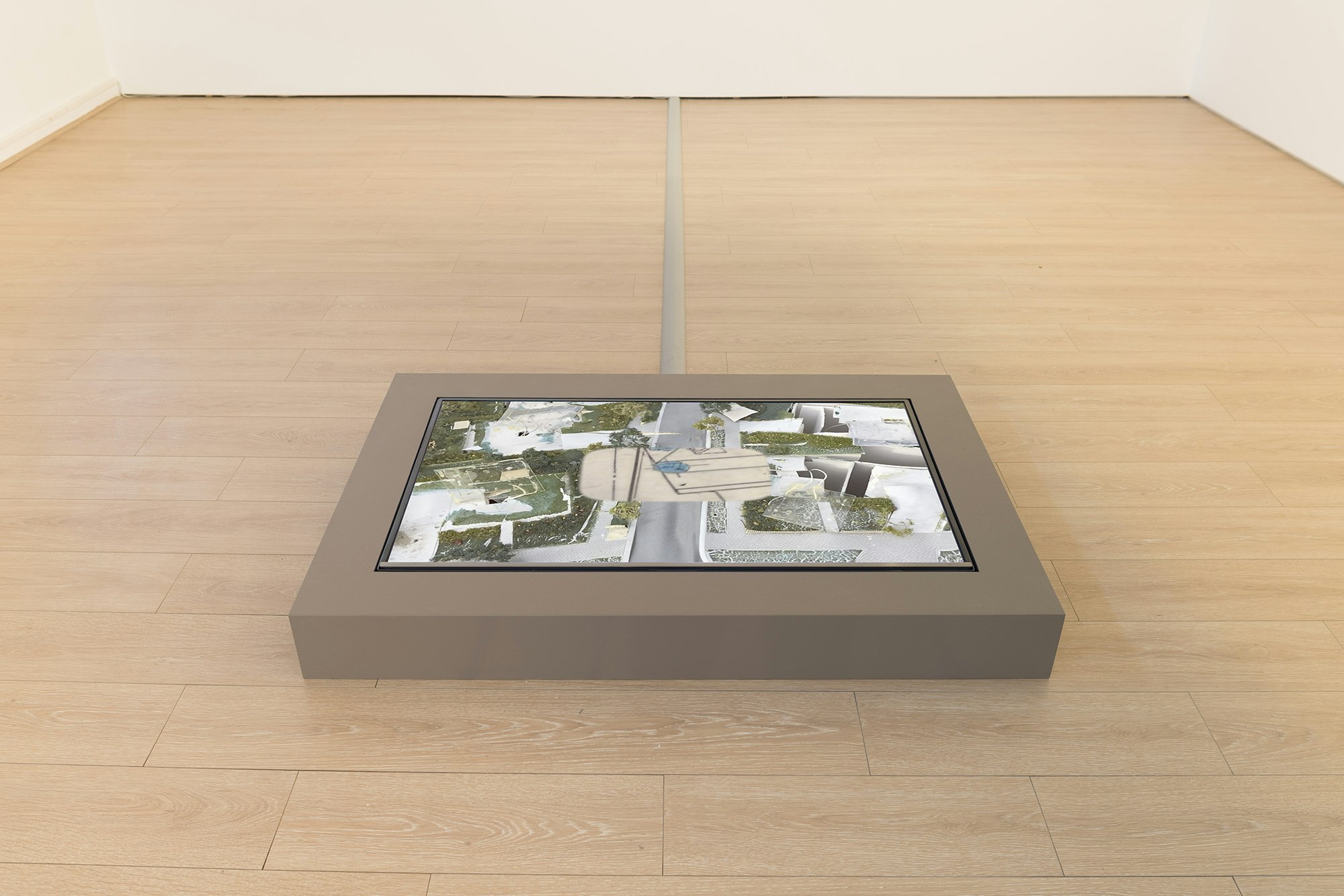 A screen installed on timber gallery floor, showing a modelled streetscape.