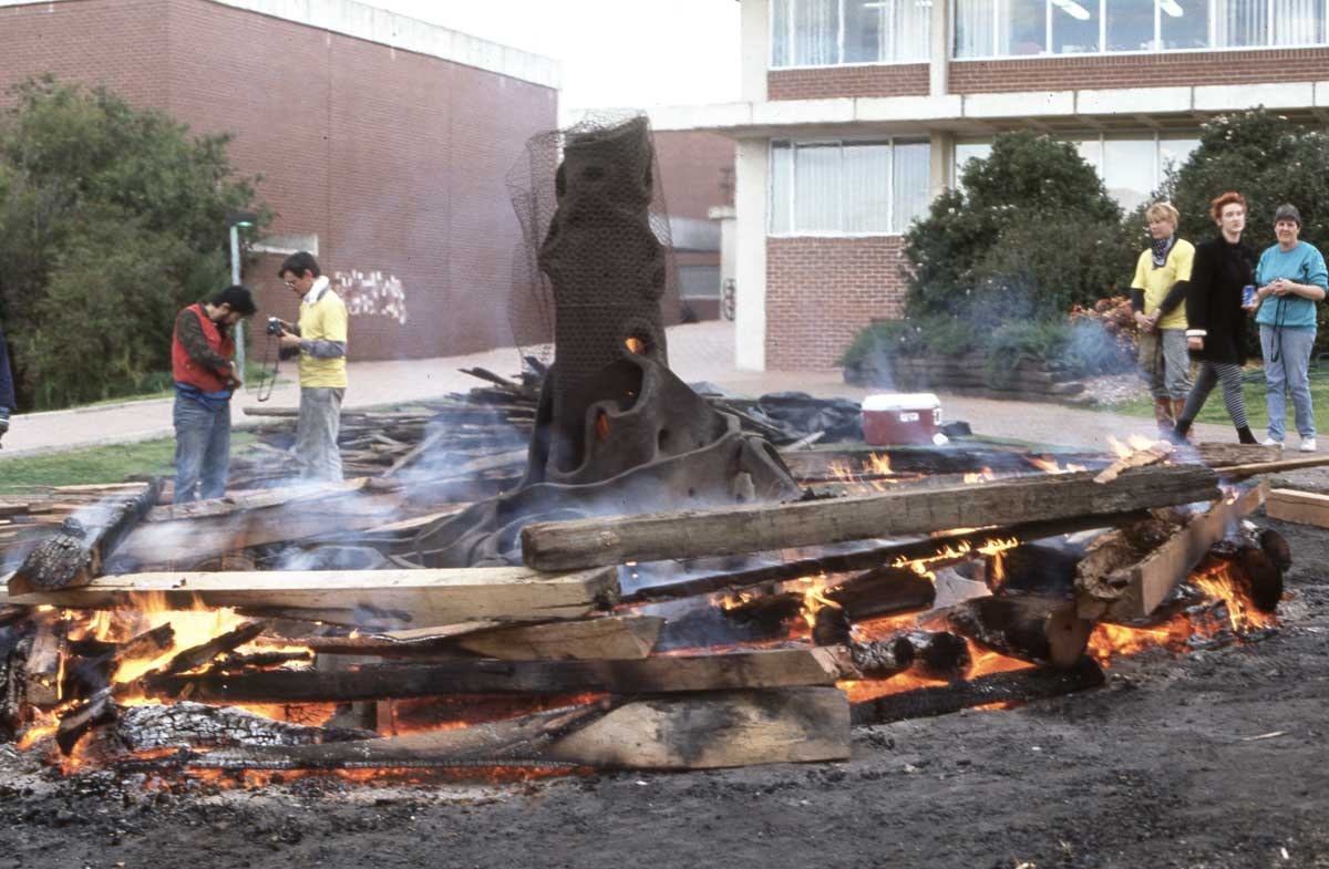 A sculpture modelled after a tree stump, wrapped in chicken wire, burns in the centre of a ring of woodfire. 