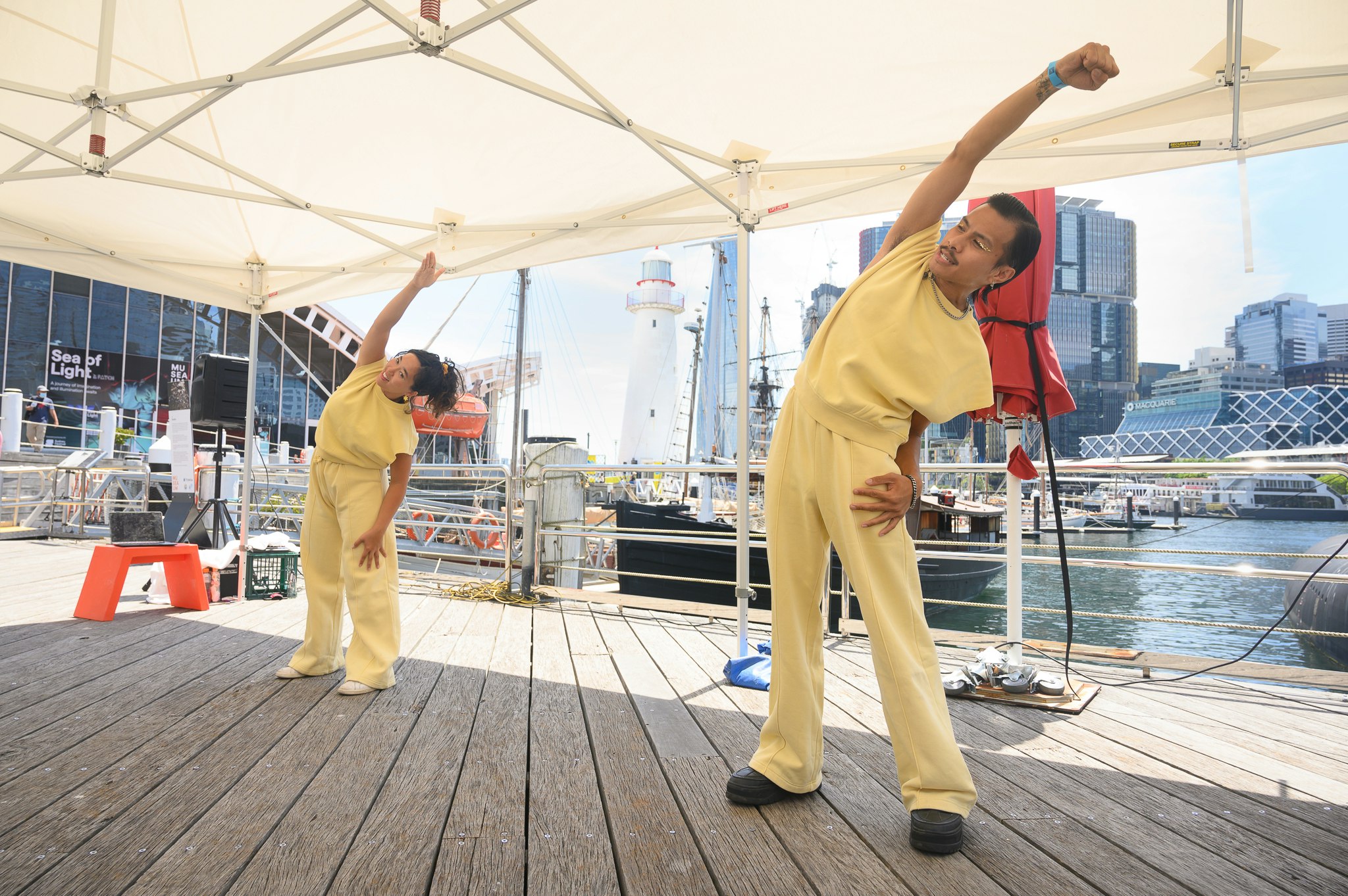 Jeremy and Reina wear matching yellow athletic outfits while doing calisthenics at the waterfront.