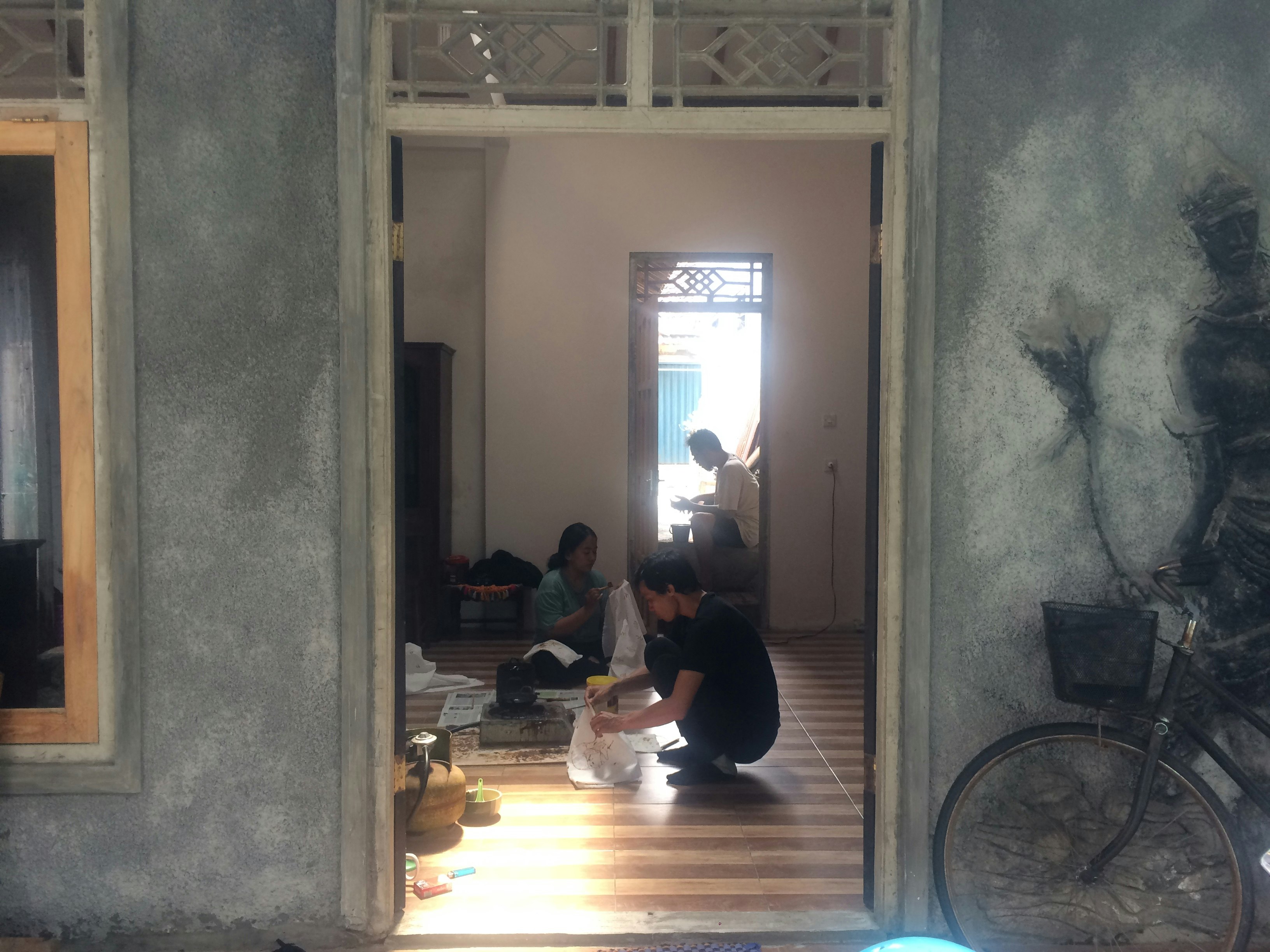 Artists squatting in a studio, holding squares of white fabric.