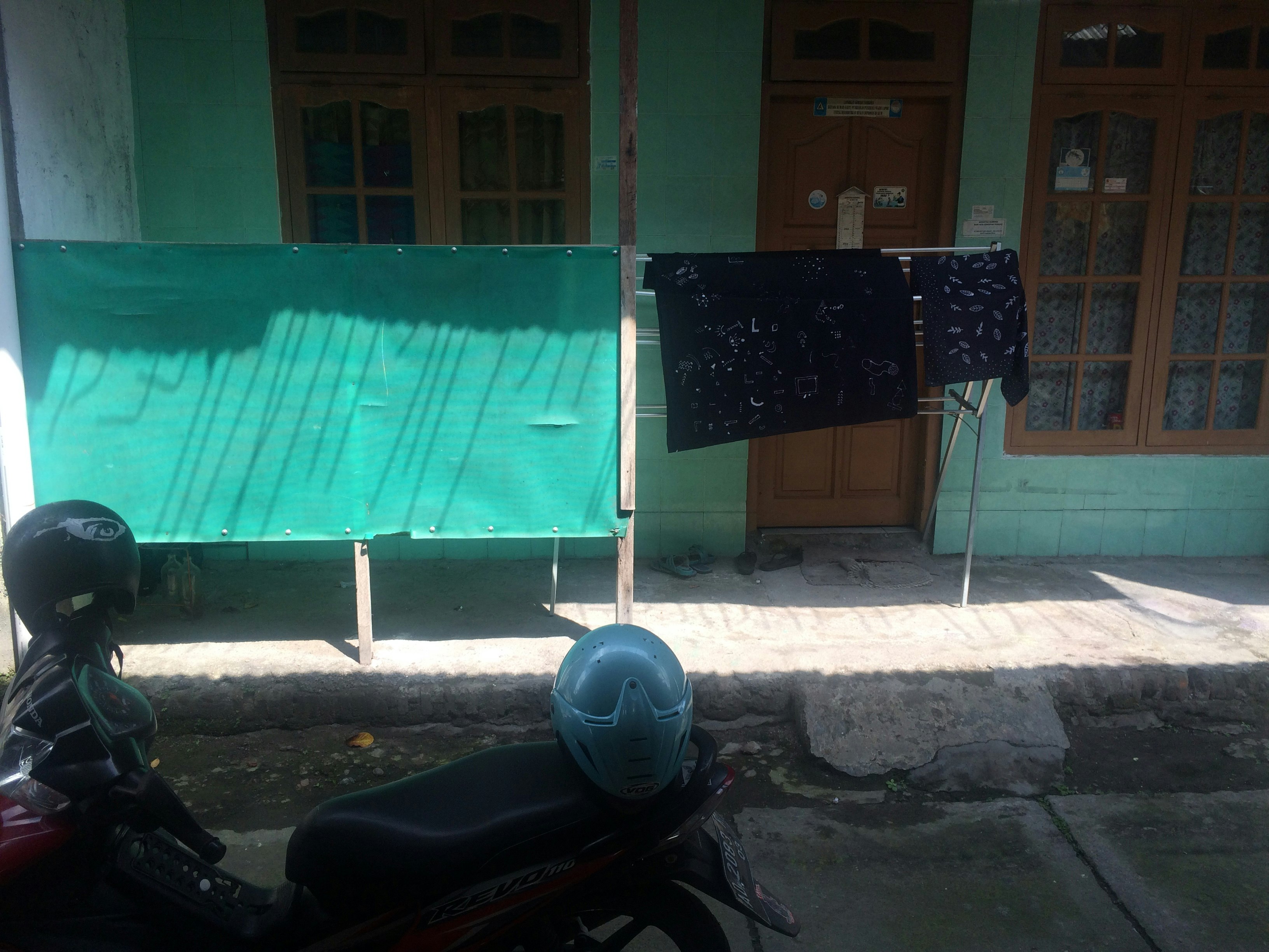 Dyed batik fabrics hanging outside a teal green house.