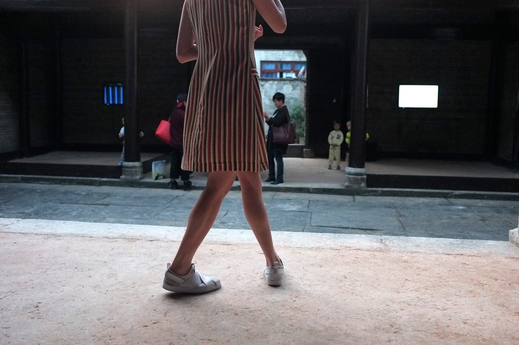 A figure in a red and blue striped dress, wearing white sneakers.