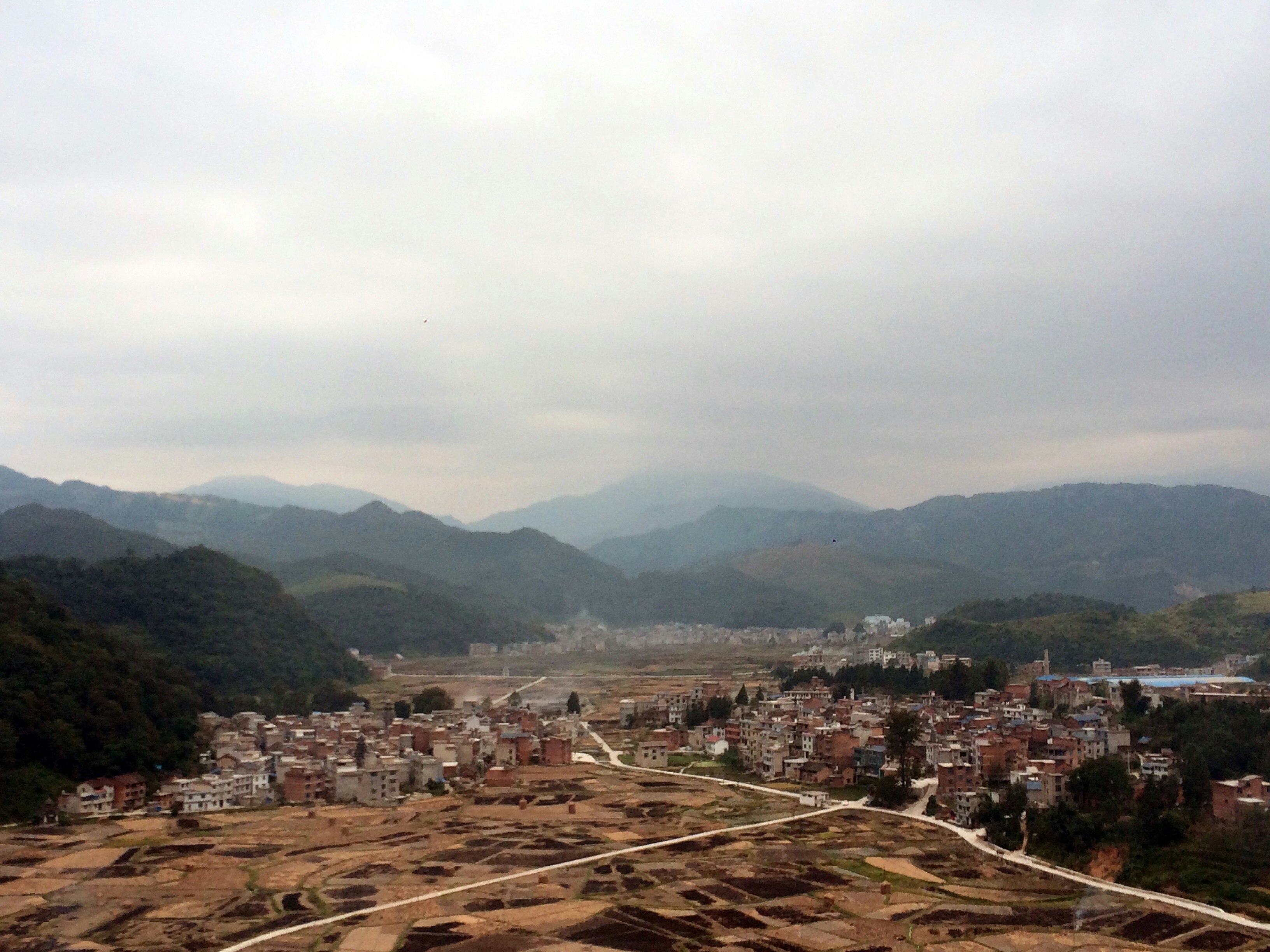 A small town surrounded by tree-covered mountains.