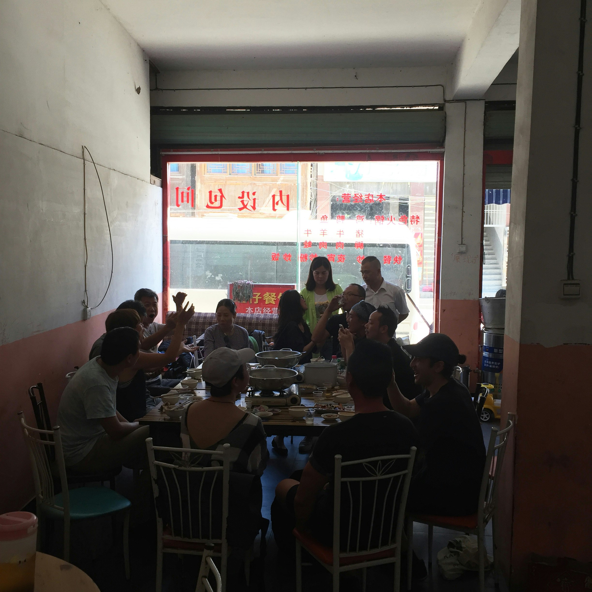 A group of diners sit around a big table in a dimly lit restaurant. 