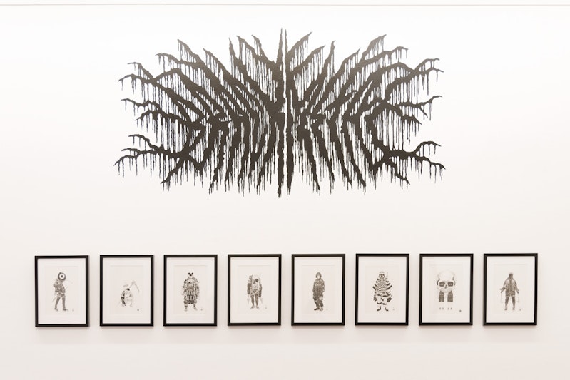 Eight framed black ink drawings on a white gallery wall. Above these drawings is a mural composed of black lines resembling tree branches or veins, stretching from a spine outwards.