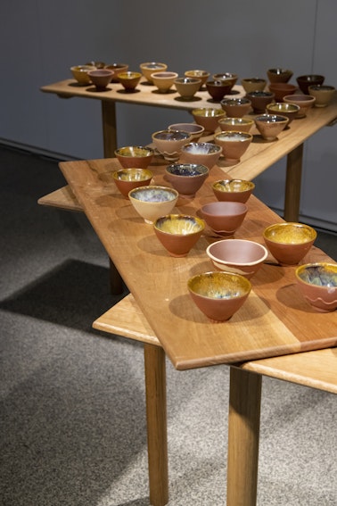 Ray Chan See Kwong, NEW RE NEW, 2018, 49 teacups: various local Chuen Lung clays, glazed and fired; produced as part of the 2018 public art and community project Hi! Hill!, by the Hong Kong Leisure and Cultural Services Department, organised by the Art Promotion Office with Curatorial Partner (art in-situ): Make A Difference Institute, Hong Kong; courtesy the artist; Mounted on River bench, recycled spotted gum bench and assorted hardwood legs, wax, by Bryden Williams of Mount Framing, commissioned by 4A Centre for Contemporary Asian Art, 2021; photo: Rhiannon Hopley for Drawn by stones, presented by 4A Centre for Contemporary Asian Art at Gallery Lane Cove + Creative Studios, 2022; courtesy the artist.