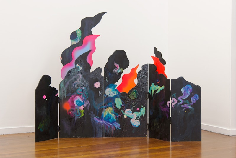 A close-up of the sculpture, cut to resemble black flame. The panels are painted with neon and pastel wisps of smoke and cloud against the black flame