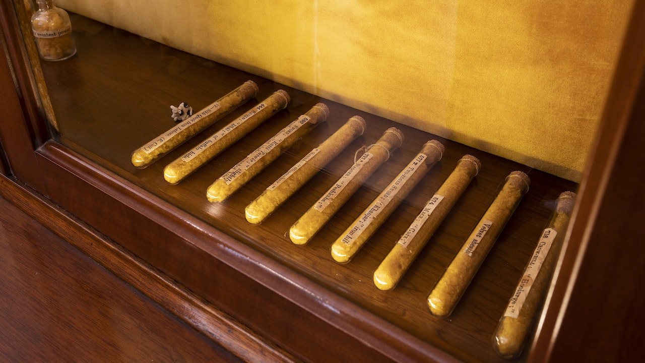 A row of nine labelled test tubes laid out at the bottom of a wooden glass cabinet