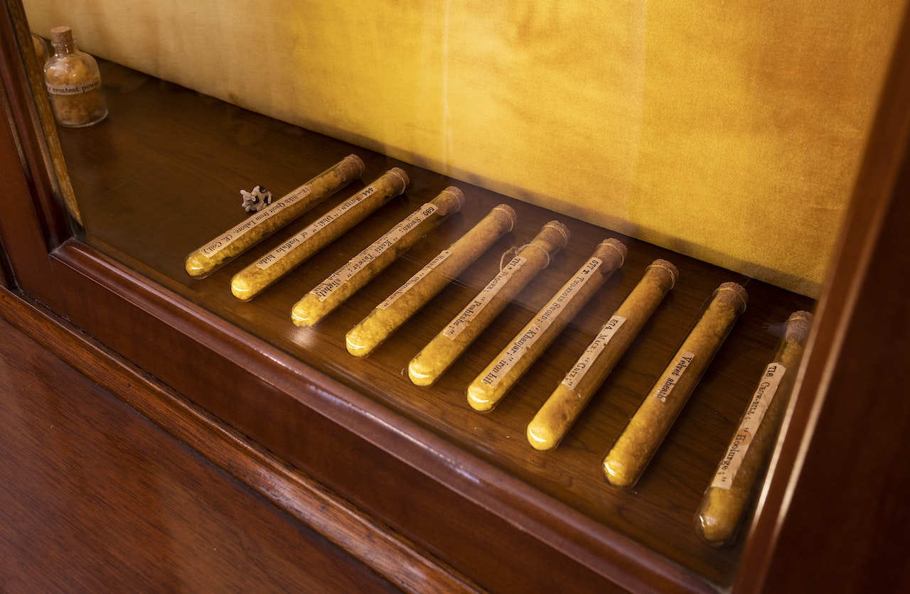 A row of nine labelled test tubes laid out at the bottom of a wooden glass cabinet