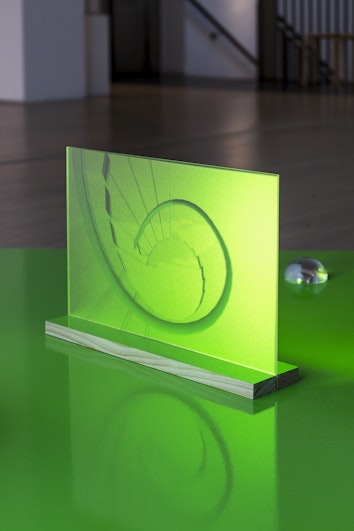 Close-up of a green-lit platform displaying a screen printed with a spiral staircase photograph