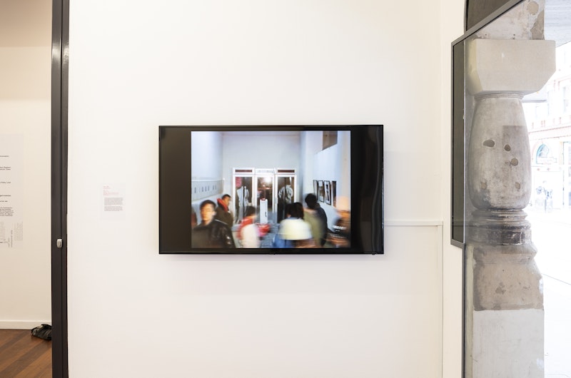 A video screen showing a group of blurred gallery visitors in movement